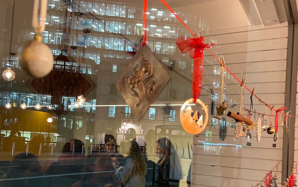A display of Christmas decorations made by BAJ staff and students hanging on red ribbon