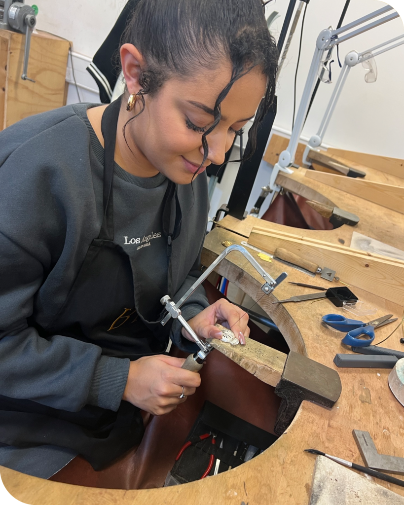 BAJ Level 3 Diploma in Jewellery Design and Manufacturing Lydia Munn using the piercing saw to cut out a design on a silver domed pendants